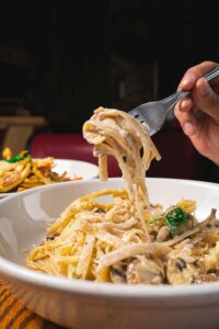 A close-up of creamy fettuccine alfredo being twirled on a fork, perfect for Italian cuisine lovers.